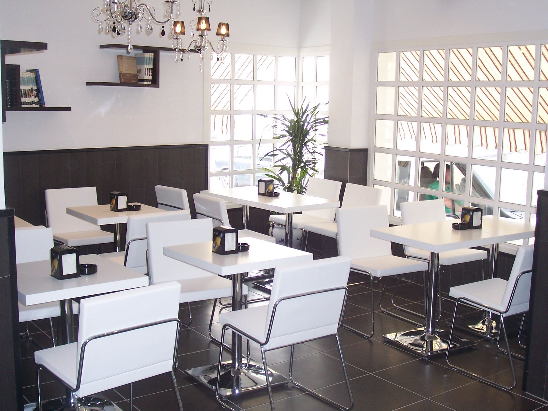 Sala de la cafetería con mesas blancas y sillas de skay
